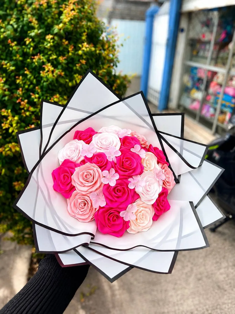 Ramo de rosas eternas fucsia y rosadas con marco de papel blanco y negro.